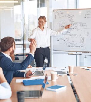 Skilled female business leader coaching interested business people, giving presentation in office.